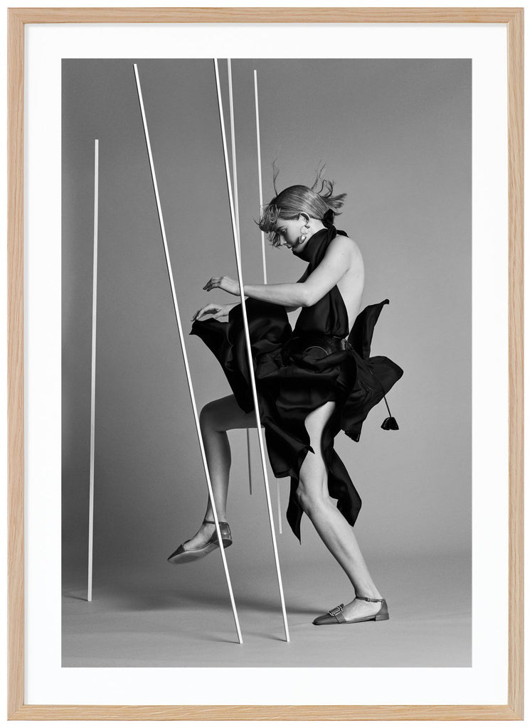 Svart-vit poster av kvinna klädd i svart sedd från sidan i fotostudio. Ekram.