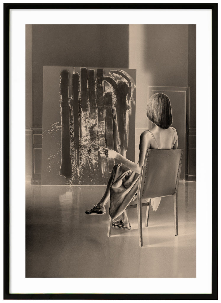Monokromt varm-tonad poster av sittande kvinna som betraktar ett konstverk. Svart ram.