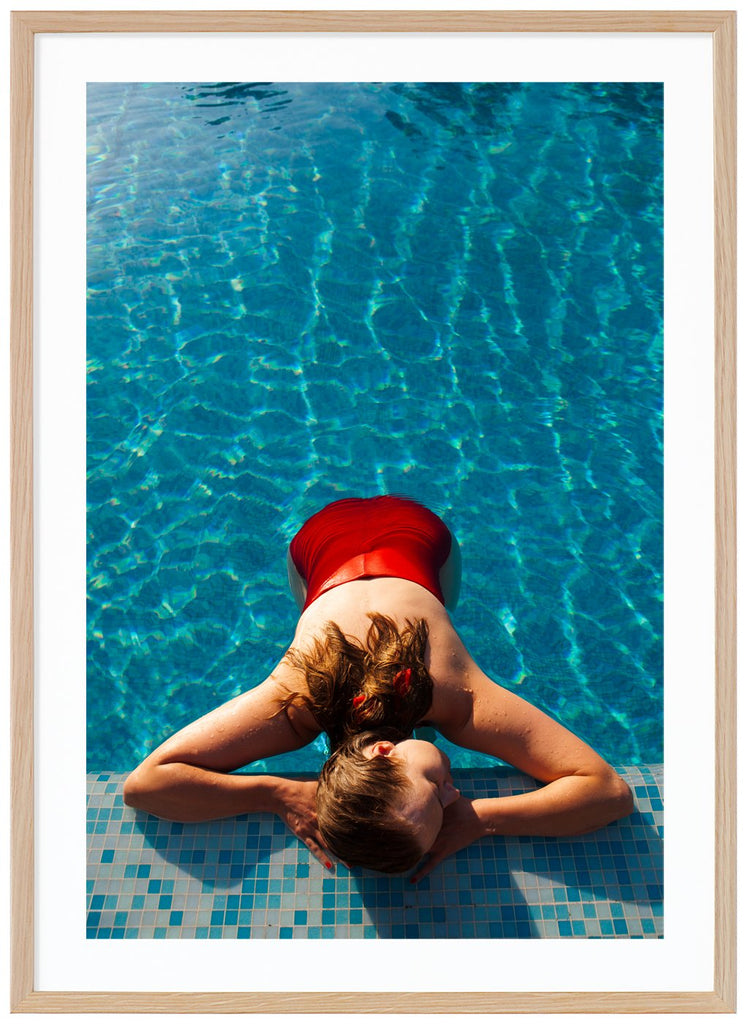 Poster av kvinna med röd baddräkt liggandes vid poolkant. Ekram.