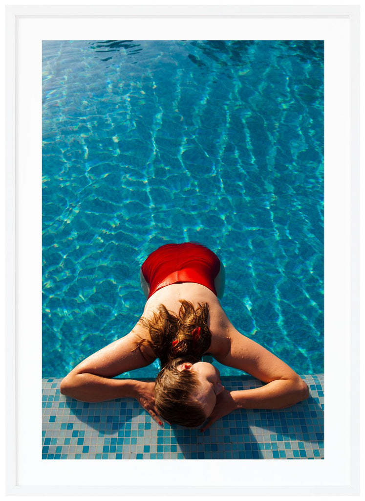 Poster av kvinna med röd baddräkt liggandes vid poolkant. Vit ram.