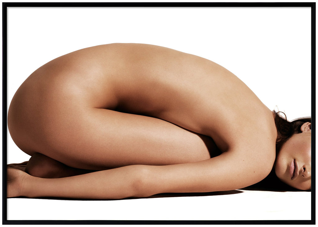 Poster av naken kvinna med magen liggandes mot låren. Svart ram.