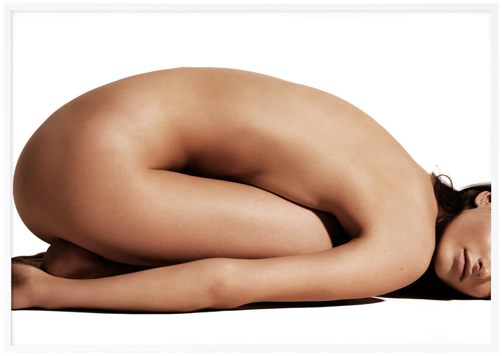 Poster av naken kvinna med magen liggandes mot låren. Vit ram. 
