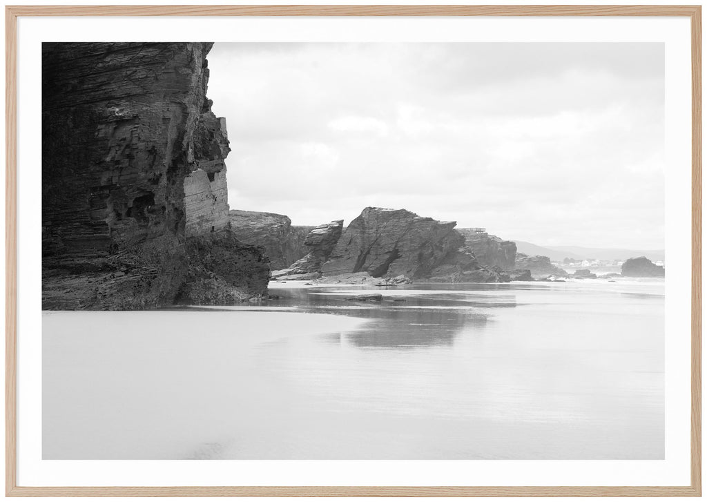 Svart-vit poster av klippor vid strand. Ekram.