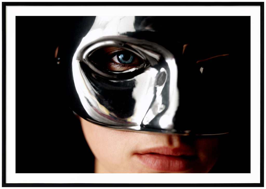 Poster av en kvinnas ansikte som bär en silvermask. Svart ram.