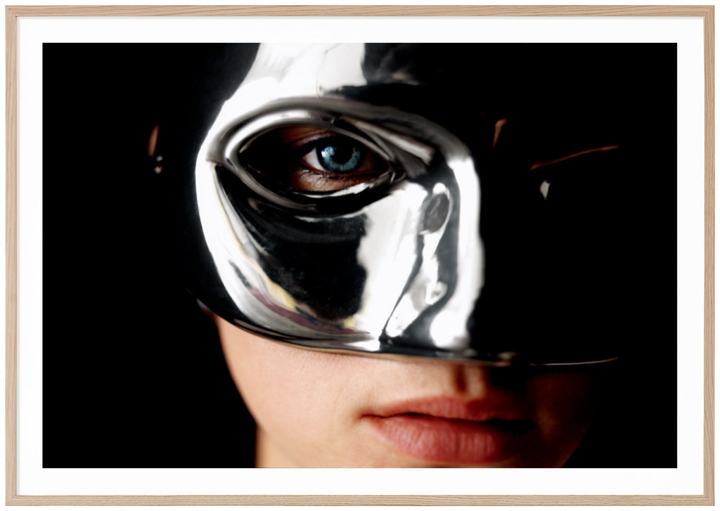 Poster av en kvinnas ansikte som bär en silvermask. Ekram.