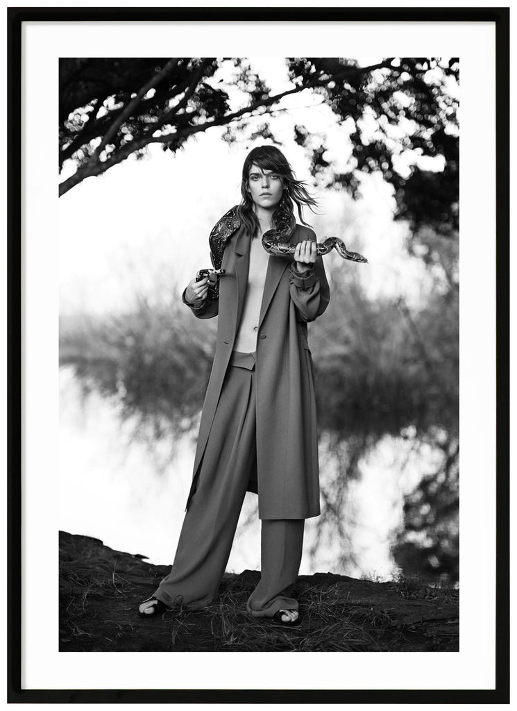 Poster av kvinna som håller i en orm skogsmiljö. Stående format. Svart ram.