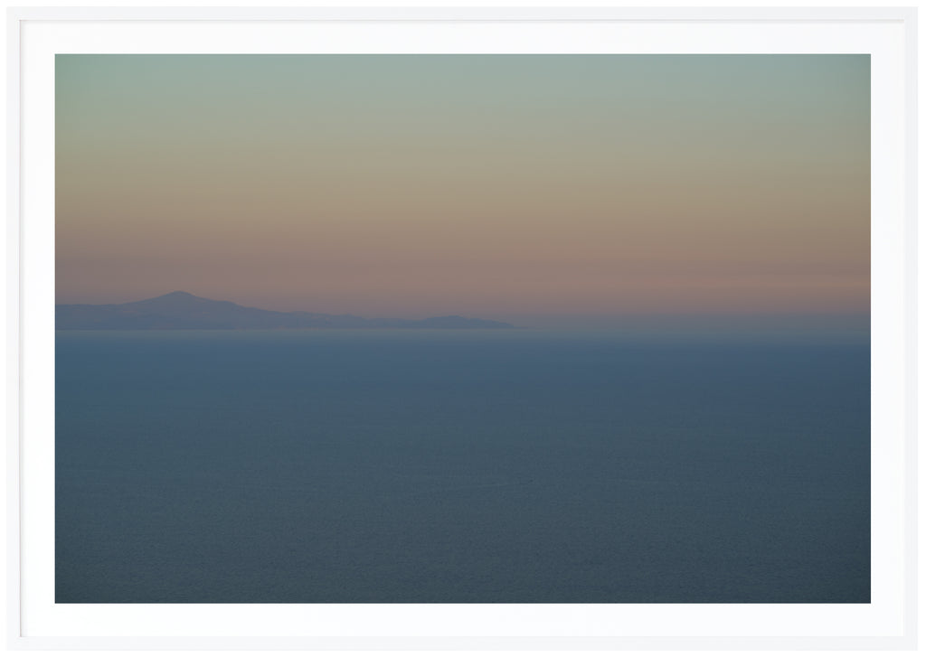 Poster av medelhavet vid Amalfikusten. Berg långt ut i havet och svaga färger i blå gul orange och rosa. Vit ram.