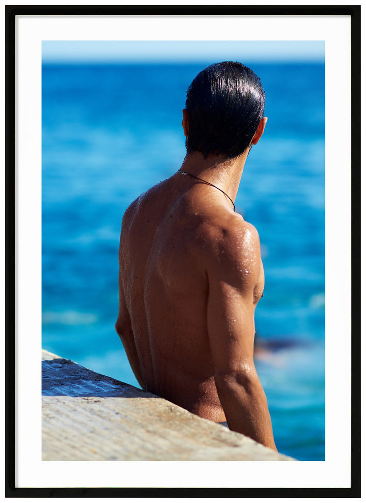 Poster av en mans nakna ryggtavla vid havet. Stående format. Svart ram.