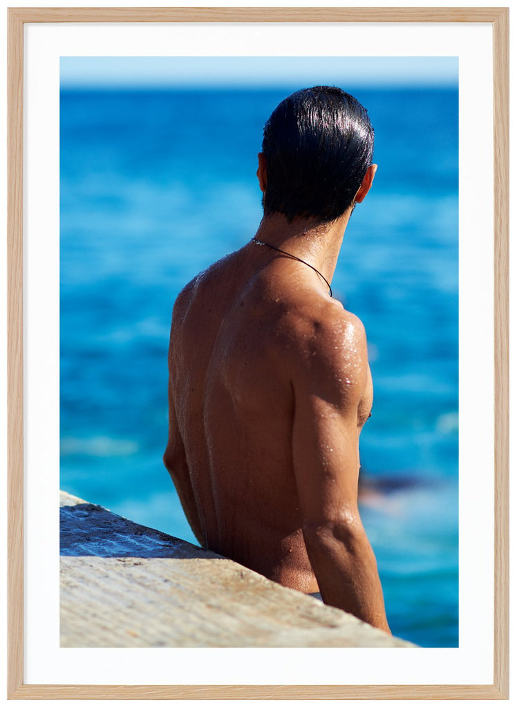 Poster av en mans nakna ryggtavla vid havet. Stående format. Ekram.