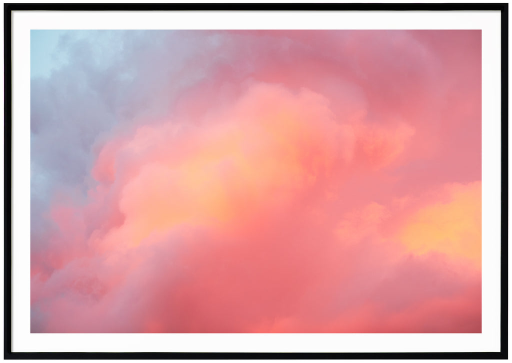 Poster av moln i blått, rosa, lila, orange. Liggande format. Svart ram.