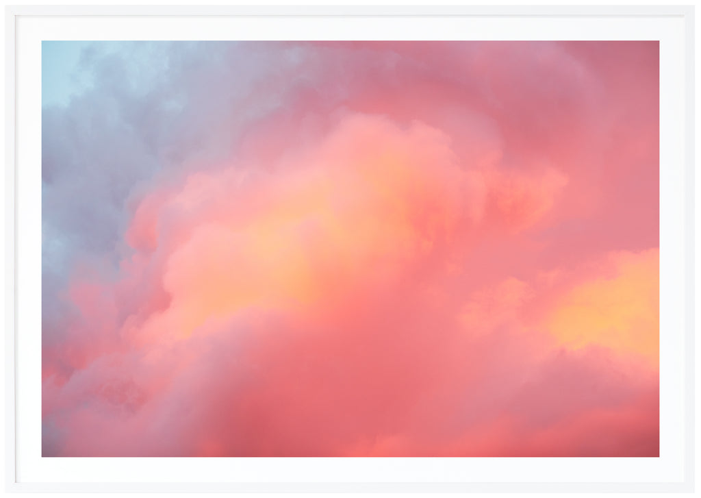 Poster av moln i blått, rosa, lila, orange. Liggande format. Vit ram.