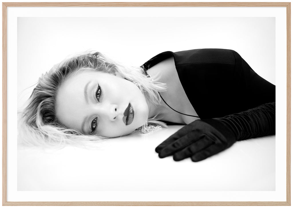 Svart-vit poster av Zara Larsson liggandes på mage med handskar. Ekram