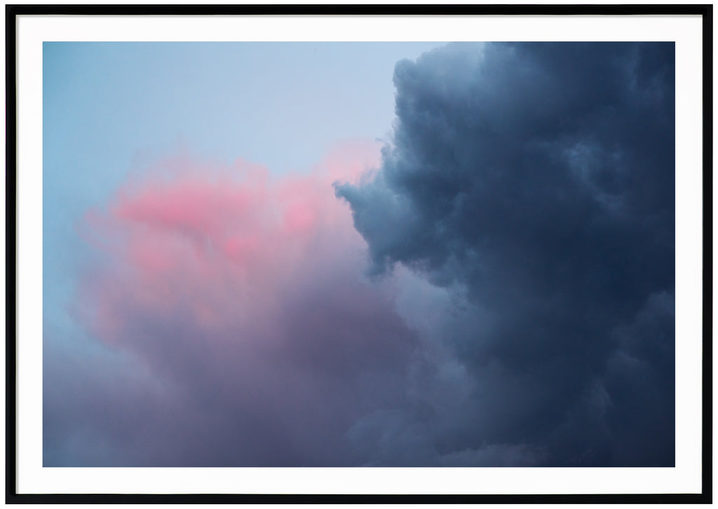 Poster av mörka blåa, rosa, lila moln. Liggande format. Svart ram.