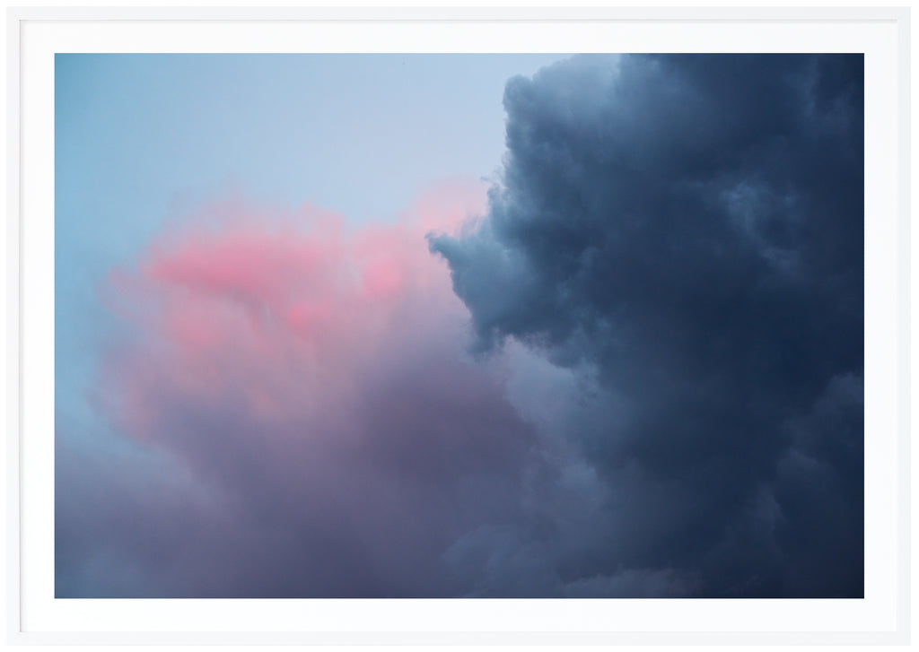 Poster av mörka blåa, rosa, lila moln. Liggande format. Vit ram.