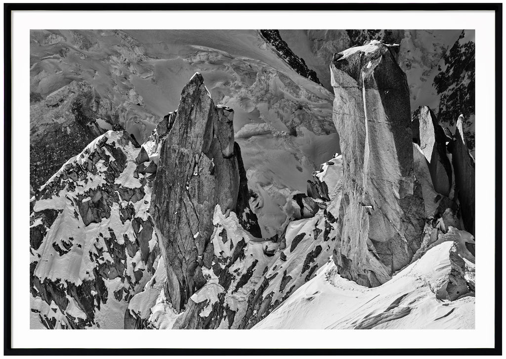  Svart-vitt fotografi av branta klippor delvis täckta av snö. Svart ram