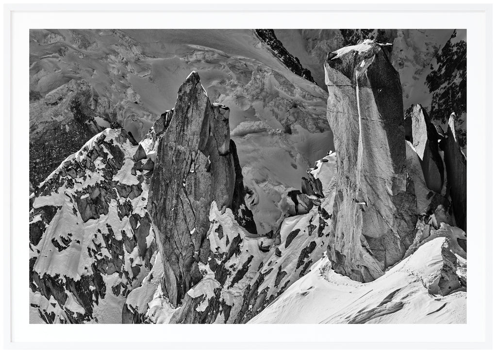  Svart-vitt fotografi av branta klippor delvis täckta av snö. Vit ram