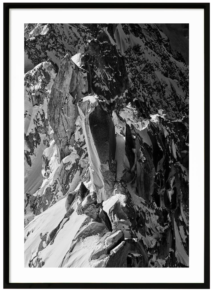 Svart-vitt fotografi av vassa klippor i alperna. Svart ram