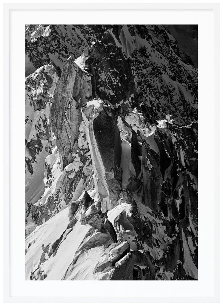 Svart-vitt fotografi av vassa klippor i alperna. Vit ram