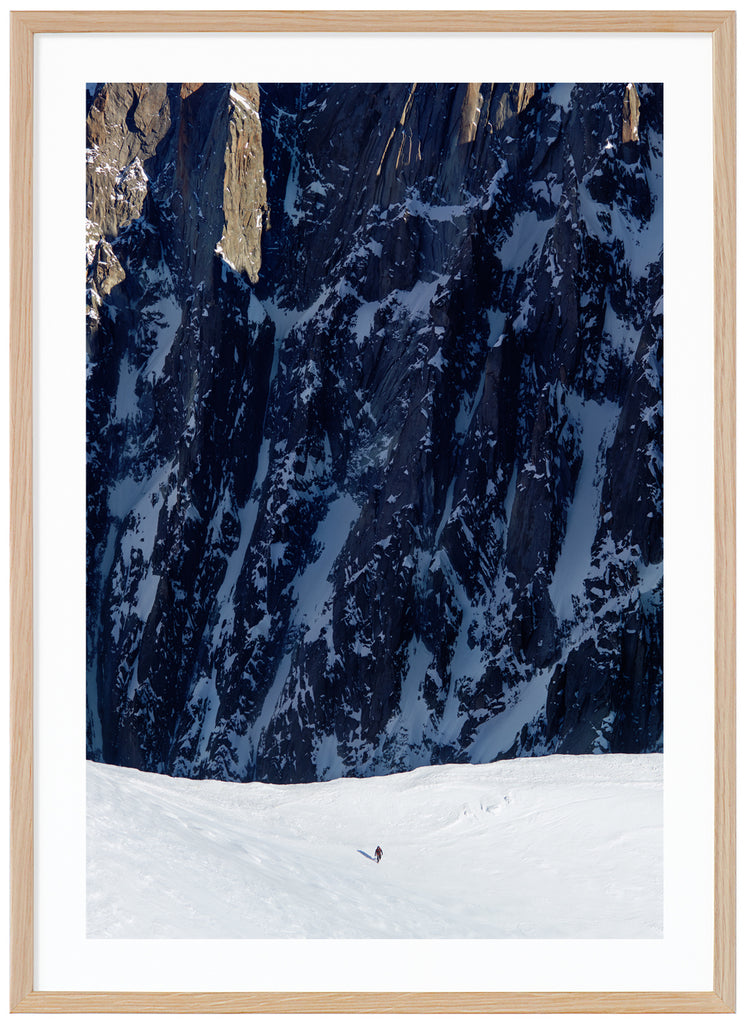 Färgfotografi av ensam bergsklättrare med branta klippor i bakgrunden. Ekram