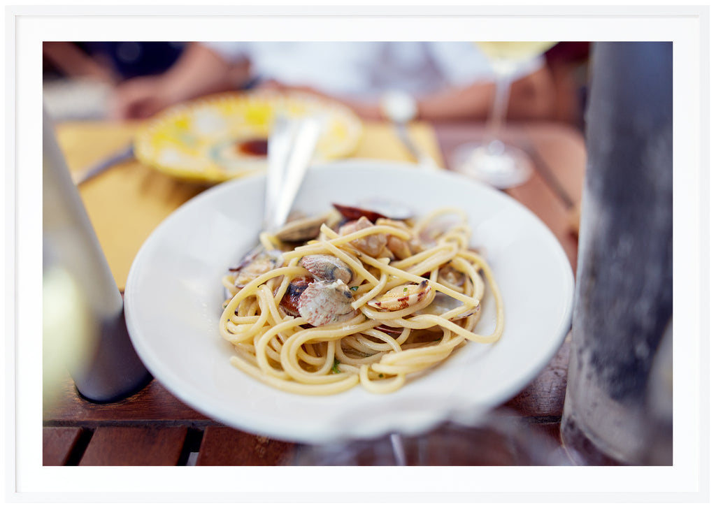 Färgfotografi av en av de mest klassiska maträtterna i Italien, Spaghetti Vongole.  Vit ram