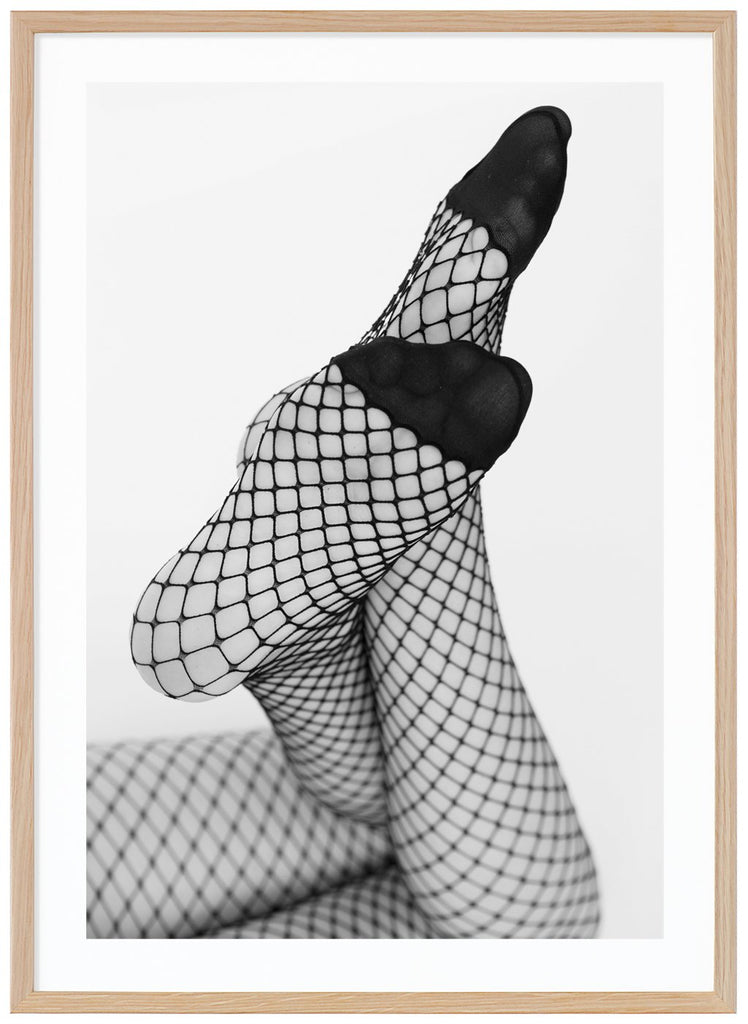 Svart-vitt fotografi av en kvinnas ben med fötterna vinklar mot kameran, hon bär nät strumpbyxor. Ekram.