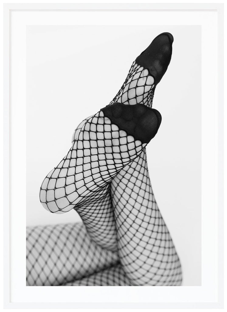 Svart-vitt fotografi av en kvinnas ben med fötterna vinklar mot kameran, hon bär nät strumpbyxor. Vit ram.