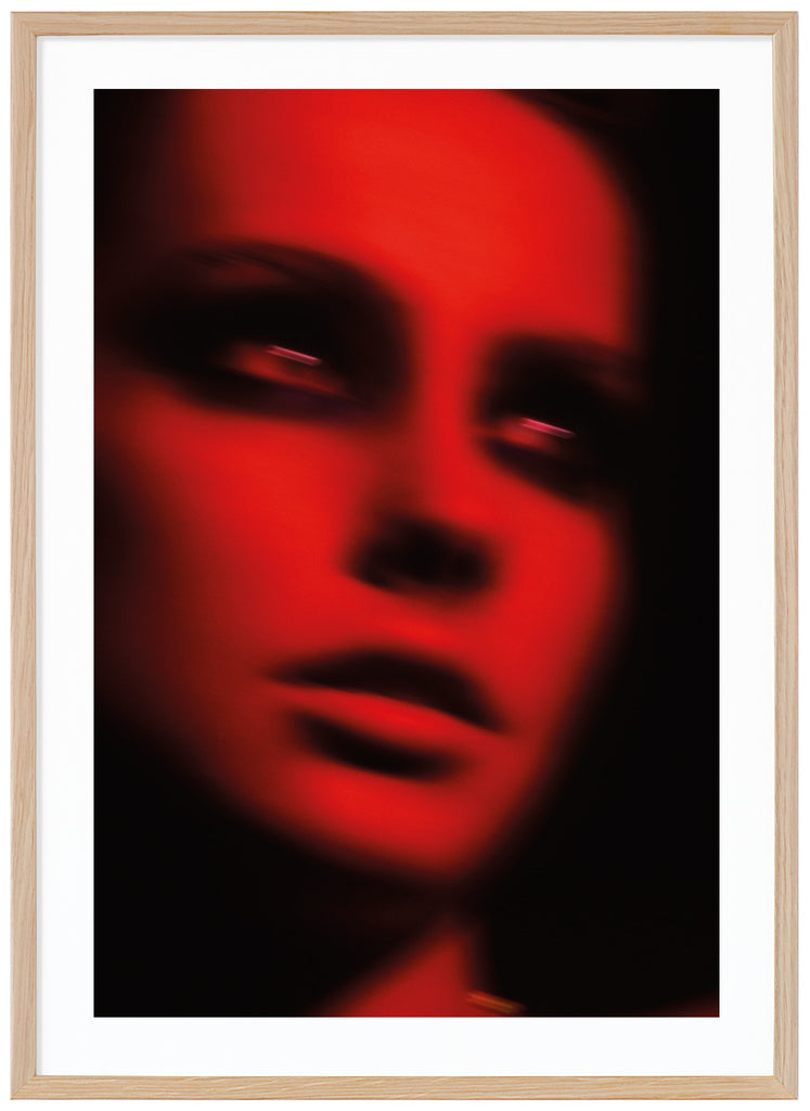 Fotografi i tonerna röd och svart, av en kvinna i svart smink runt ögonen. Ekram. 