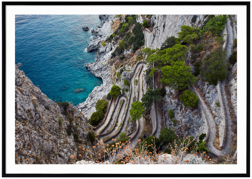 Fotografi i färg av utsikt över ett promenadstråk i sten på Italienska ön Capri. Svart ram. 
