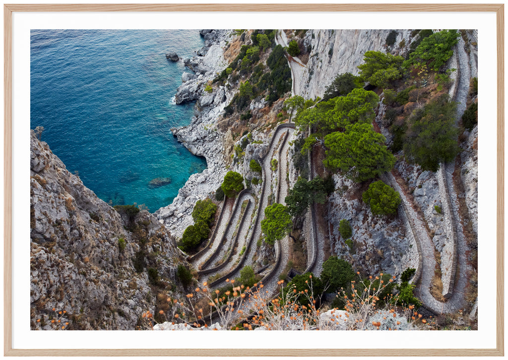 Fotografi i färg av utsikt över ett promenadstråk i sten på Italienska ön Capri. Ekram.