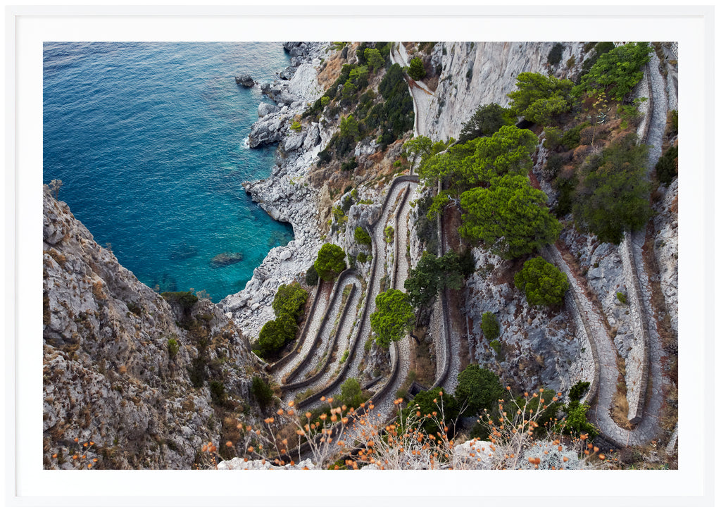Fotografi i färg av utsikt över ett promenadstråk i sten på Italienska ön Capri. Vit ram.
