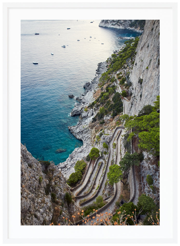 Fotografi i färg av utsikt över ett promenadstråk i sten på Italienska ön Capri. Verticale.  Vit ram. 
