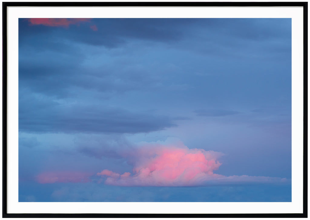 Fotografi av moln i färgerna blå och rosa. Svart ram.