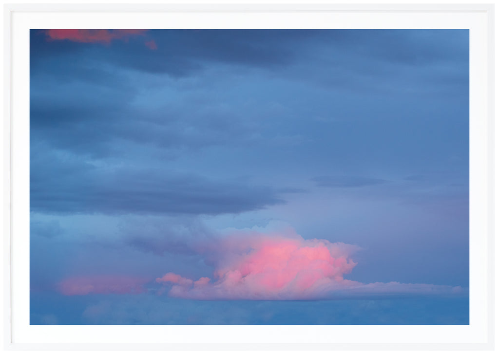 Fotografi av moln i färgerna blå och rosa. Vit ram.
