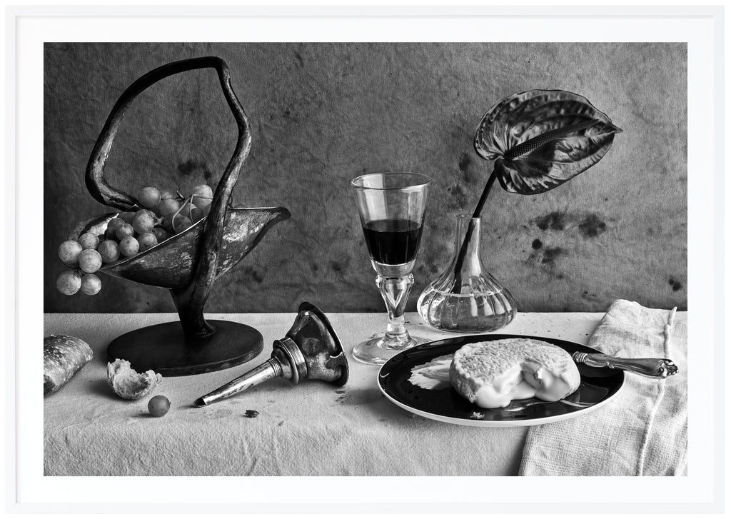 Svart-vit poster av dukat bord med ost, vin och vindruvor. Kanvas-bakgrund. Liggande format. Vit ram.